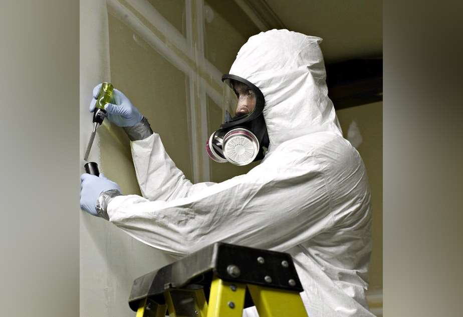 Mand i beskyttelsesdragt, igang med at fjerne asbest